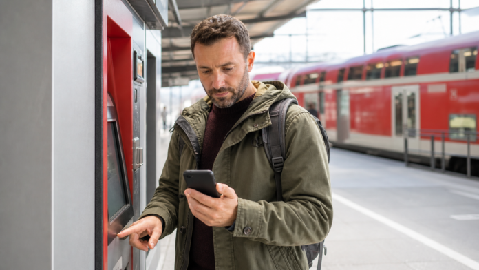 Laenderticket oder Deutschlandticket Reisender am Bahnhof vergleicht Deutschlandticket und Laenderticket als Symbolbild fuer die Ticketwahl